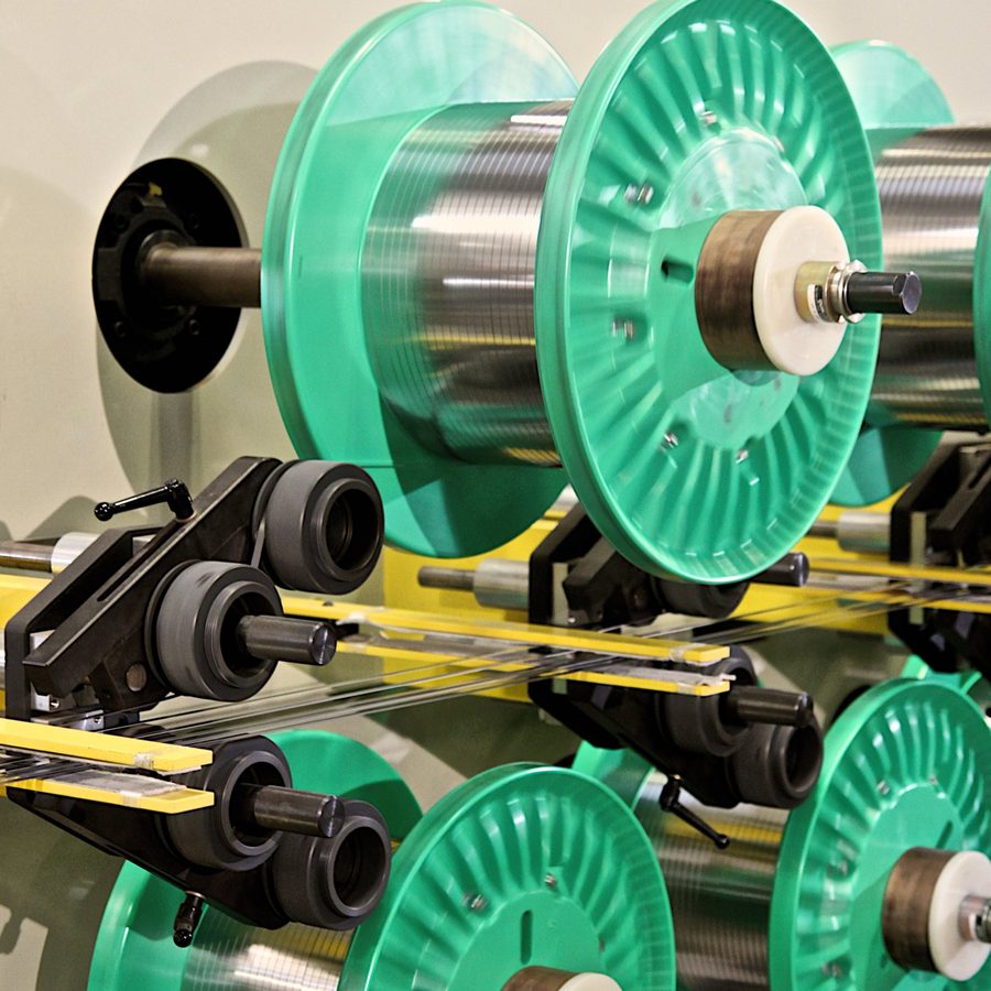 Narrow strip being oscillate wound onto spools on a traverse winding line.