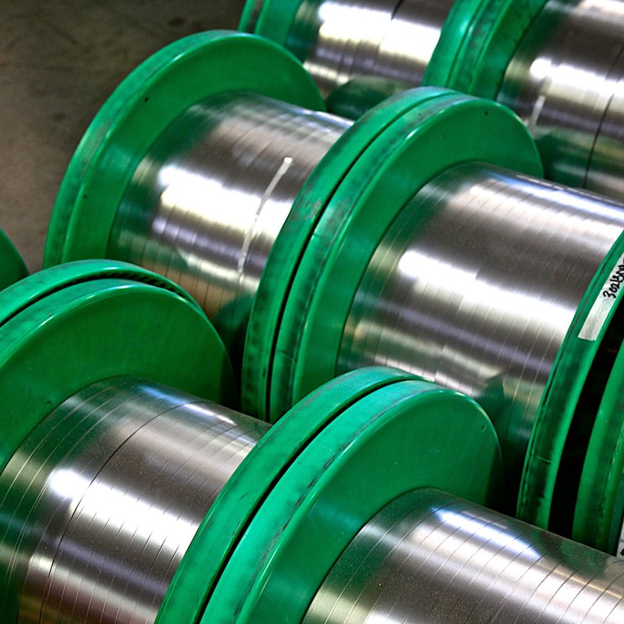 Narrow stainless strip oscillate wound on spools, with the strip laid in rows across the width of each spool.